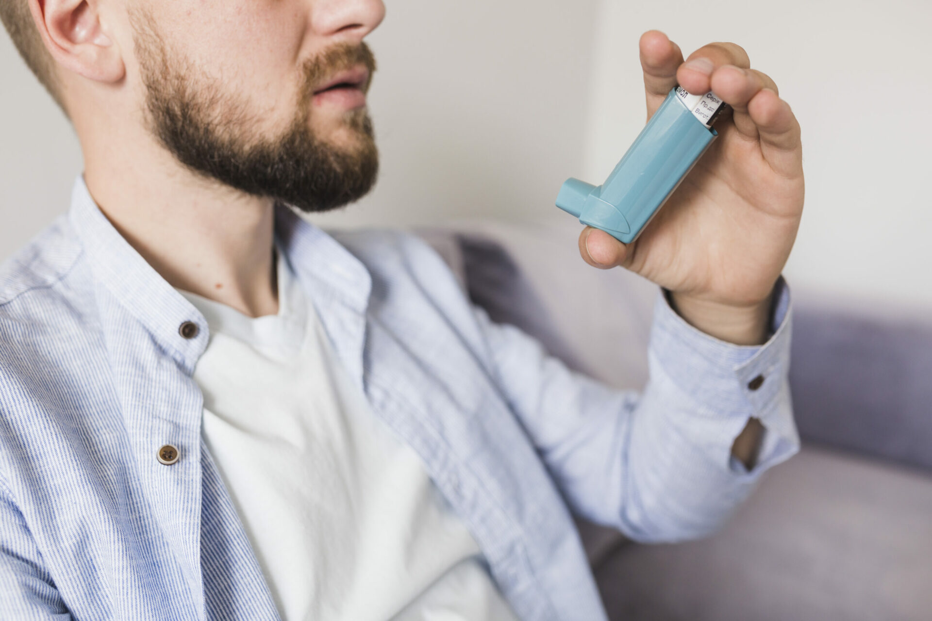 Young adult male using an inhaler