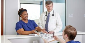 Javara desk employee handing clipboard to another employee and doctor