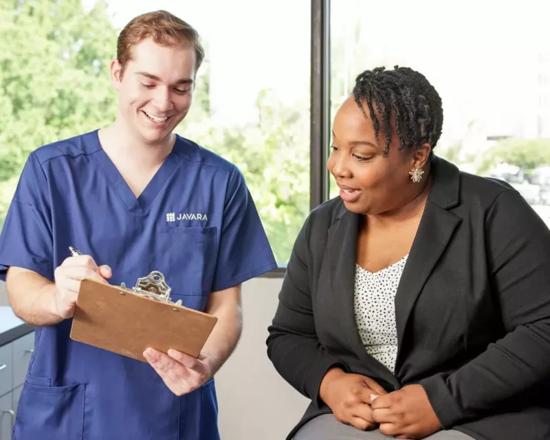 Javara HCP holding a clipboard and showing patient the contents of the clipboard