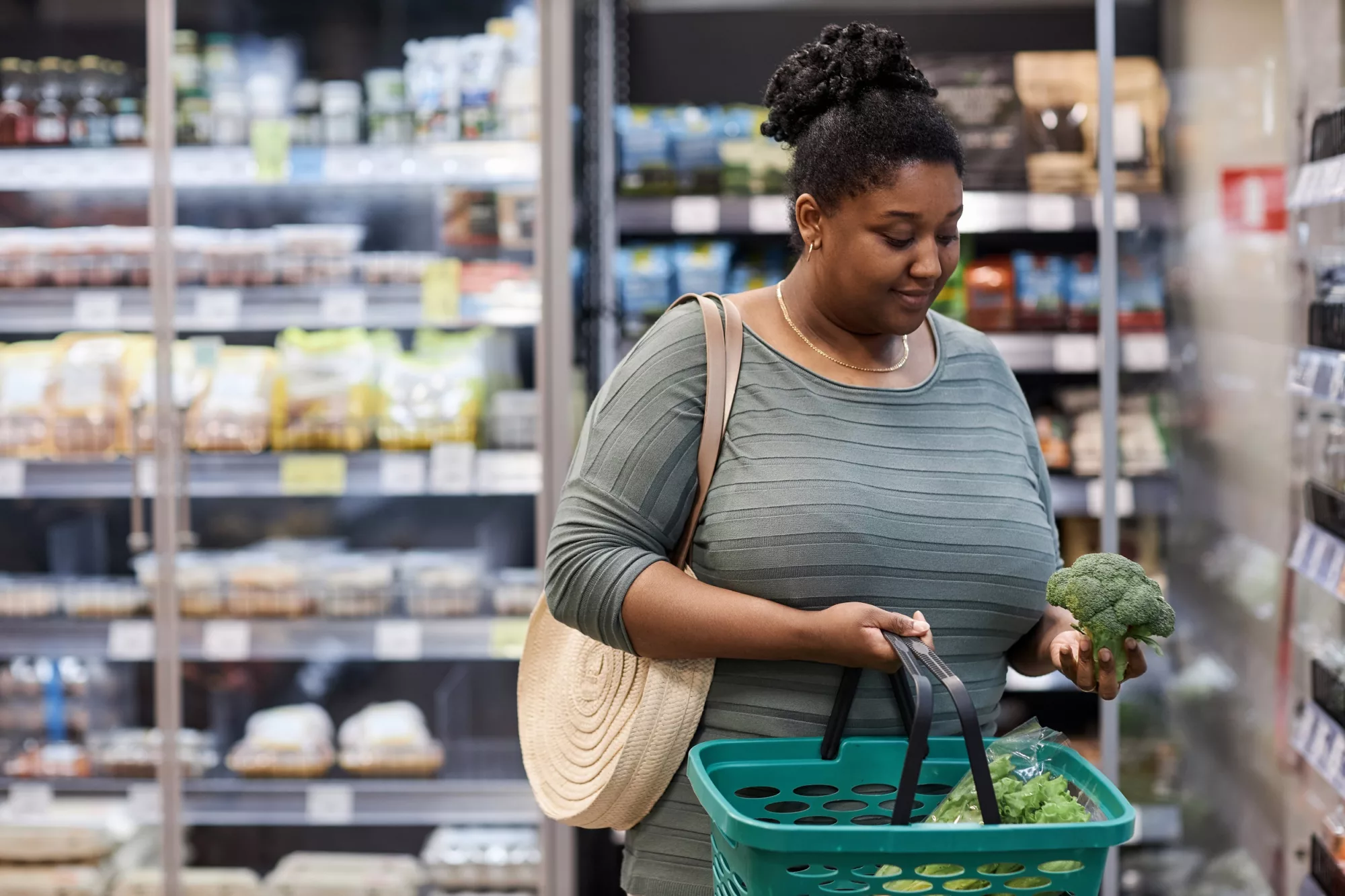 Waist up portrait of real black woman buying fresh vegetables in supermarket, copy space